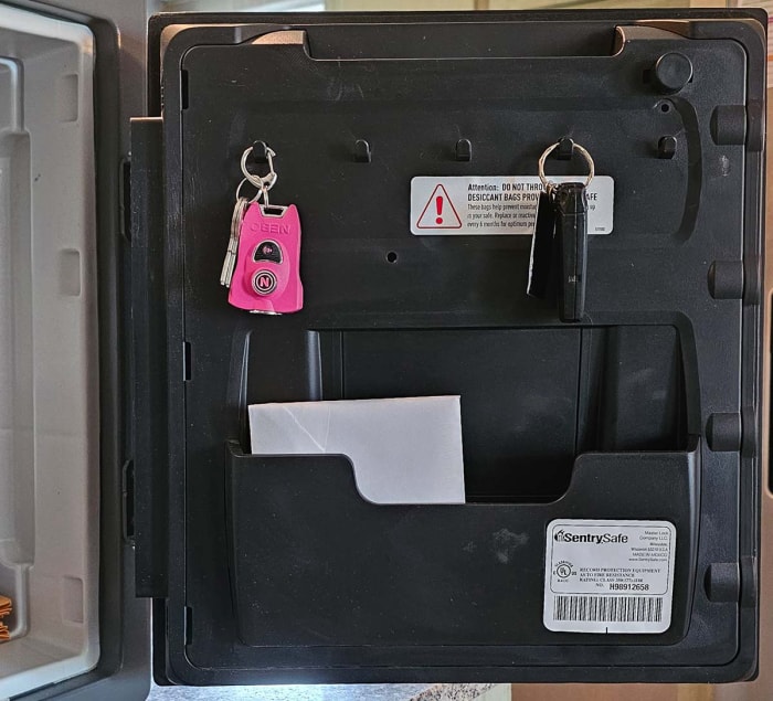 A l'intérieur de la porte de SentrySafe'avec deux jeux de clés suspendus et un document dans une poche.