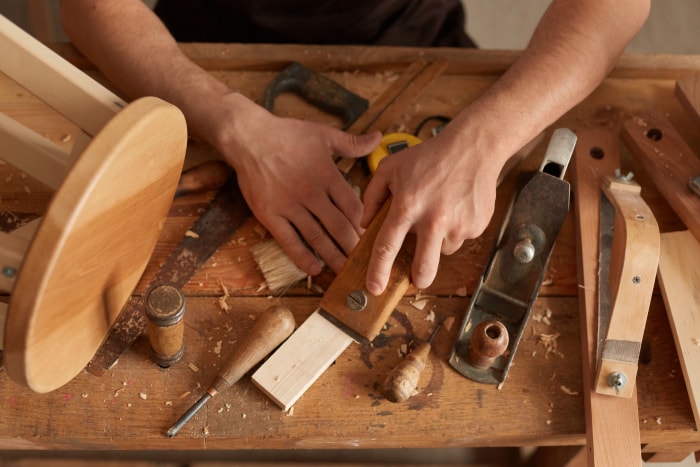 Vue rapprochée du dessus d'un charpentier travaillant et courbant du bois dans son atelier, fabriquant des produits en bois dans sa menuiserie.