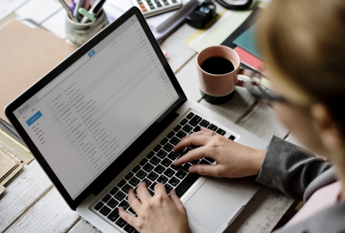 Une femme parcourt ses e-mails sur un ordinateur portable dans un bureau à domicile.