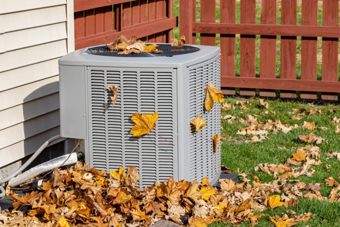 Les feuilles mortes s'accumulent autour d'un climatiseur.