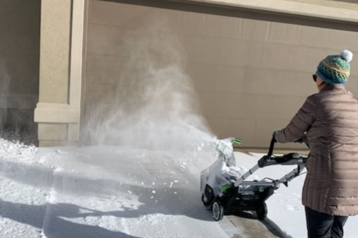 Quelqu'un utilise la souffleuse à neige légère Ego pour souffler la neige d'une allée.