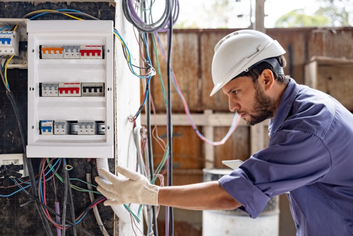 Électricien travaillant sur un tableau électrique.