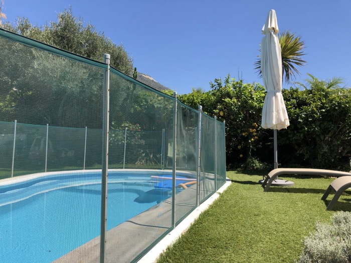 Une haute clôture grillagée entourant une piscine creusée.