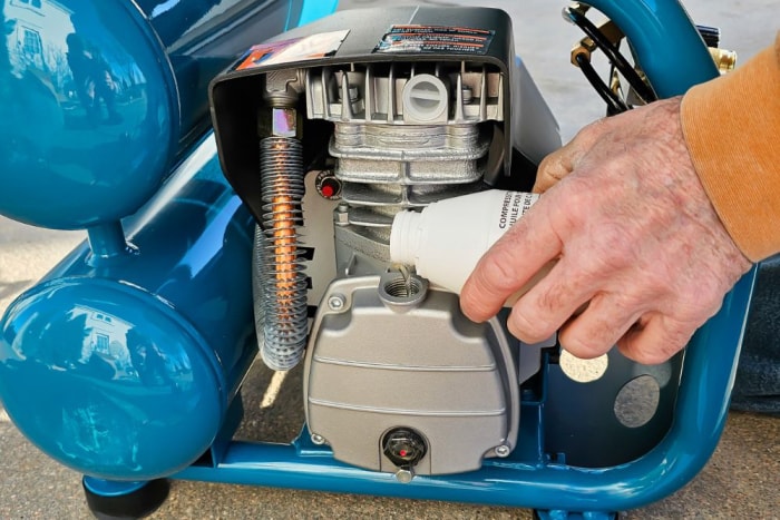 Une personne ajoutant de l'huile au compresseur d'air Makita MAC2400 pendant les tests.