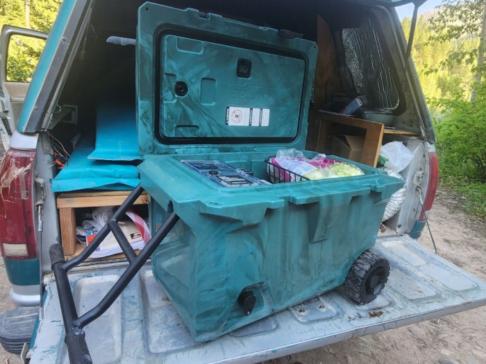 Glacière à roulettes Brumate turquoise à l'arrière d'un camion dans les bois