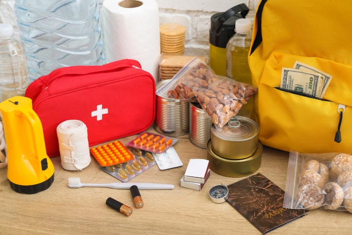 Nécessités pour un sac d'urgence sur une table en bois, comprenant une trousse de premiers soins, des médicaments, de la nourriture et plus encore.