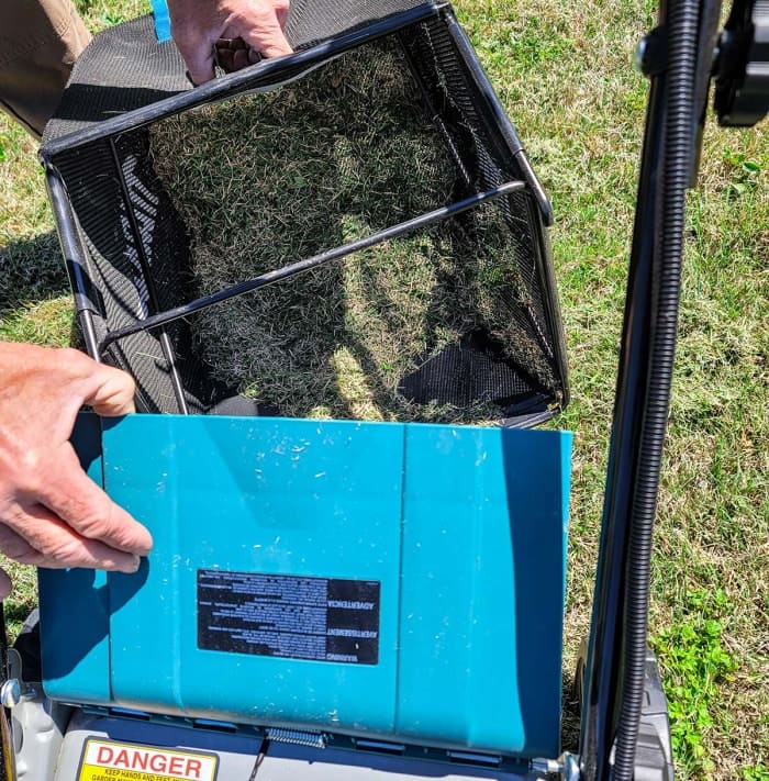 Homme vidant le sac de la tondeuse Makita de l'herbe coupée