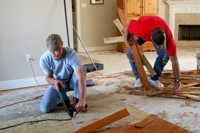 Deux ouvriers retirent un plancher endommagé. 