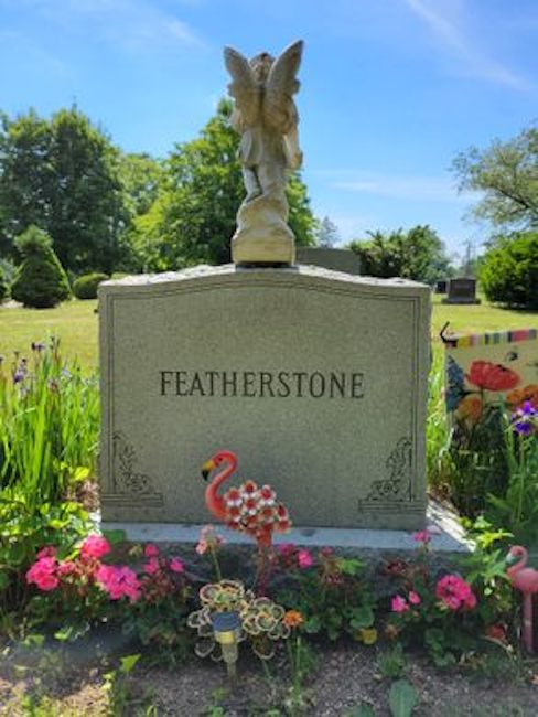 tombe familiale en pierre de plume avec un flamant rose devant et des fleurs