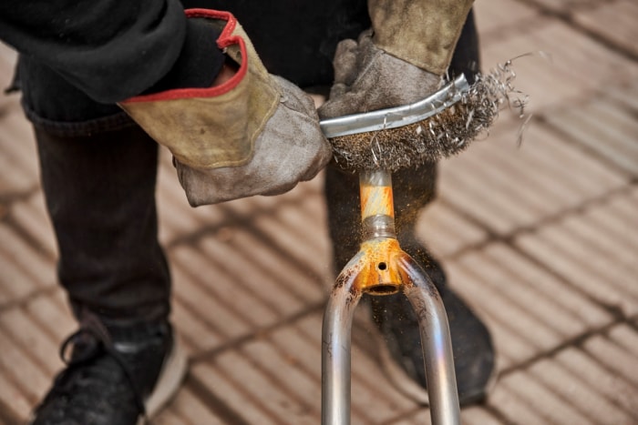 Personne utilisant une brosse métallique pour enlever la peinture du métal.