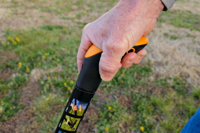 La main d'une personne sur la poignée du désherbeur vertical Fiskars pendant le test.