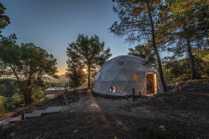 Une maison en forme de dôme avec des fenêtres circulaires devant un coucher de soleil.