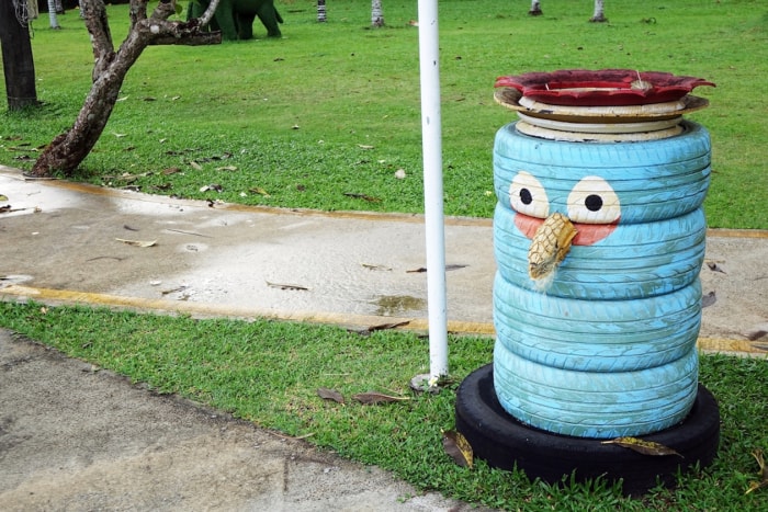 Une poubelle fabriquée à partir de vieux pneus avec un visage peint dessus dans un parc