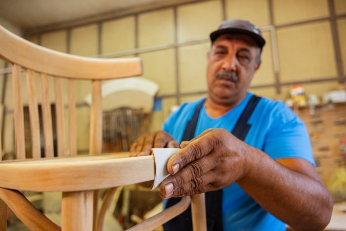 Menuisier indien fabriquant une chaise en bois. Élimination des surfaces rugueuses sur le bois.