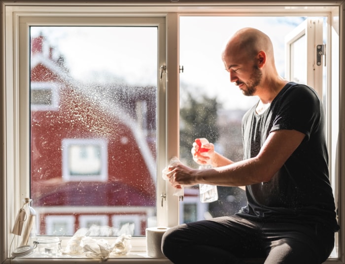 Un homme nettoie une fenêtre avec du papier.