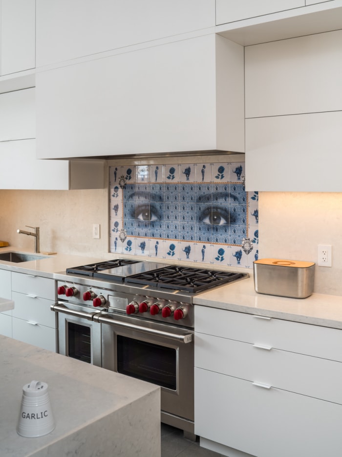 Cuisine blanche avec un dosseret de cuisinière en mosaïque bleu et blanc représentant des yeux photoréalistes