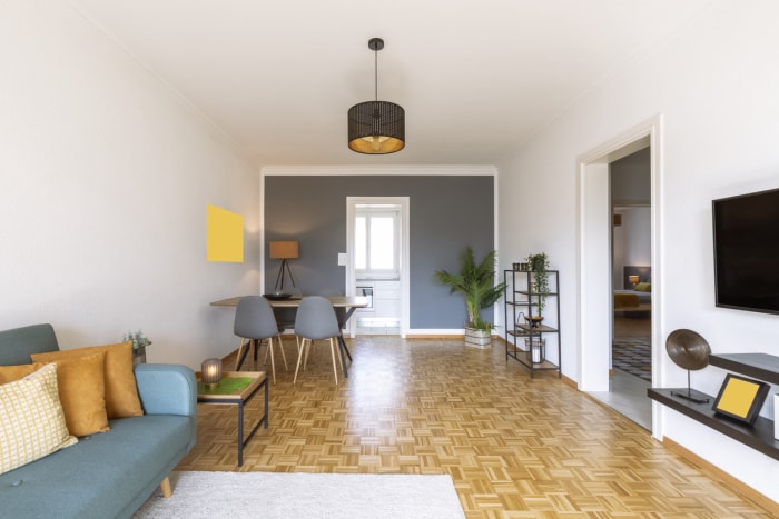 Salon étroit avec mur du fond peint en gris foncé.