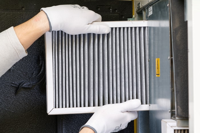 Des mains gantées remplacent le filtre du climatiseur.