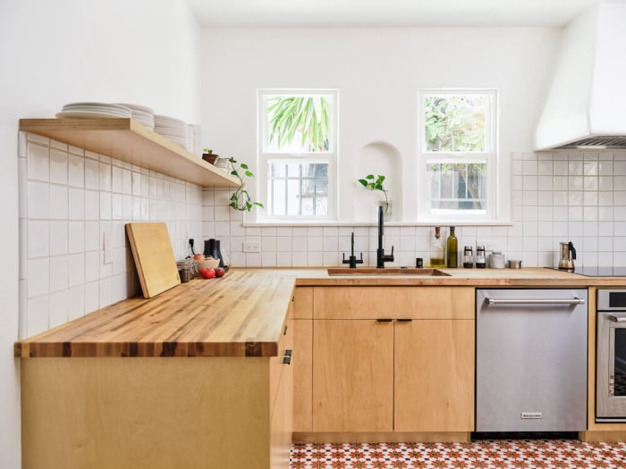 Cuisine lumineuse de style scandinave avec un dosseret en carrelage blanc et des comptoirs, des armoires et des étagères en bois clair