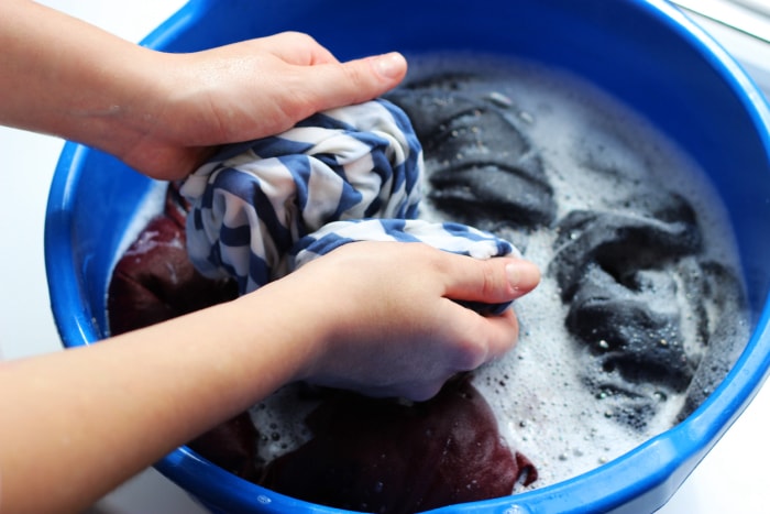 Une femme lave ses vêtements avec ses mains dans de l'eau savonneuse. Lavage des vêtements à la main. Photo de haute qualité