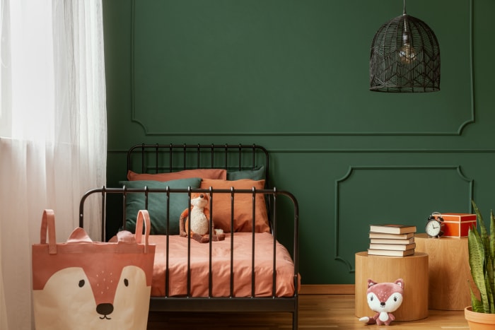 Chambre d'enfant avec peinture murale vert émeraude et lit simple couleur saumon.