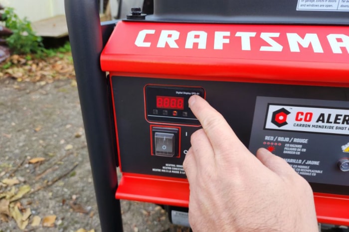 Une personne appuie sur le bouton de démarrage du générateur Craftsman de 6 000 watts pendant les tests.