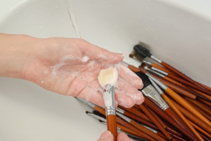 laver le pinceau de maquillage avec du savon et de la mousse dans l'évier