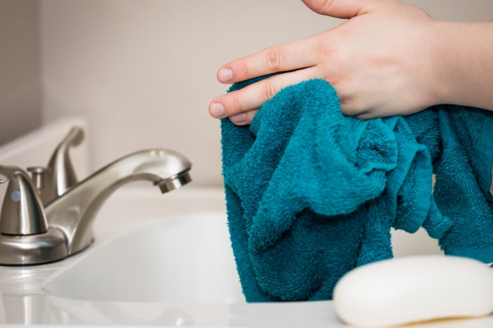 vue rapprochée d'une serviette verte utilisée pour se sécher les mains au lavabo de la salle de bain