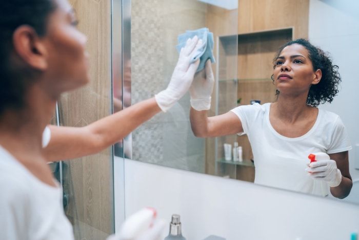 utilisations du peroxyde d'hydrogène - femme utilisant un nettoyant en spray sur un miroir