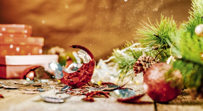 Une décoration de Noël cassée sur une surface en bois avec des aiguilles de pin et d'autres décorations de Noël.