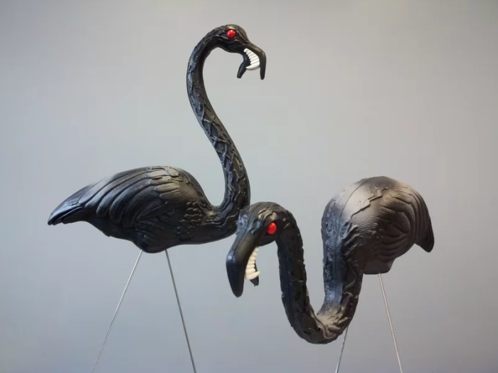 deux flamants roses en plastique noir avec des crocs et des yeux rouges