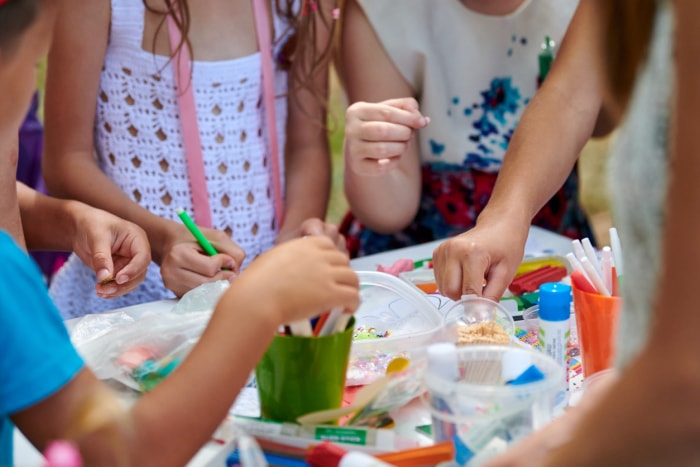 Un groupe d'enfants se sont réunis autour d'une table d'artisanat avec des fournitures d'art pour faire de l'artisanat.