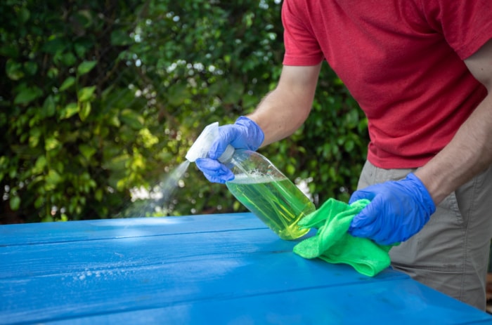 utilisations du peroxyde d'hydrogène - homme pulvérisant une solution nettoyante sur une table bleue