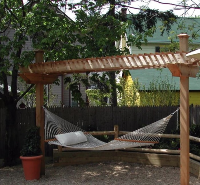 Scène d'arrière-cour avec un hamac suspendu à une pergola en bois. 