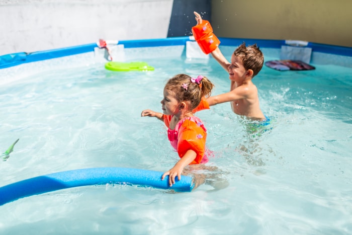 Un garçon et une fille jouent dans la piscine, excités par l'arrivée de l'été.