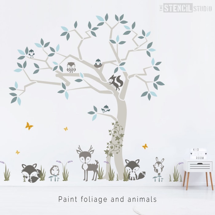 Un mur est peint avec une scène d'arbre forestier avec des animaux dans des couleurs grises et pastel.