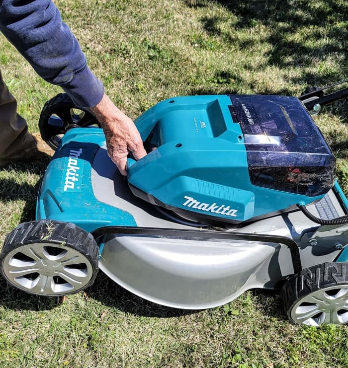 Un homme soulève une tondeuse à gazon Makita