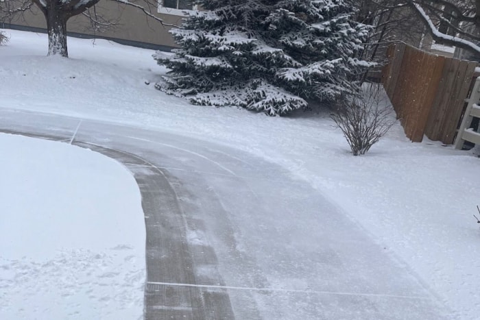 Une large courbe de trottoir déblayée de la neige à l'aide de la souffleuse à neige légère Ego.