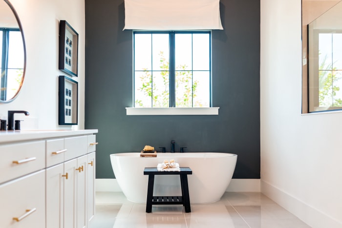 Salle de bain blanche et moderne avec un mur d'accent bleu foncé derrière une baignoire.