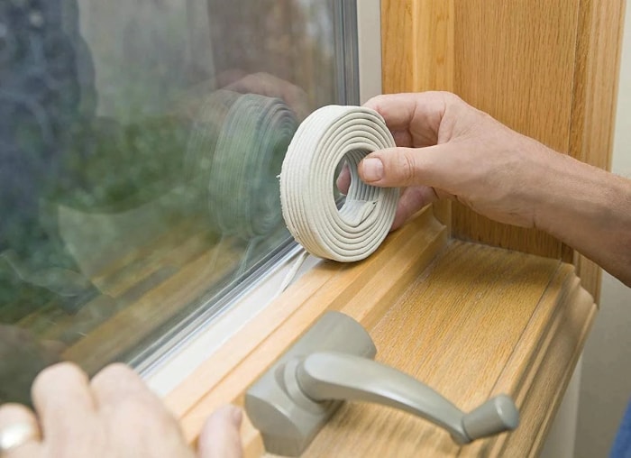 Mains utilisant un rouleau de mastic sur la fenêtre.