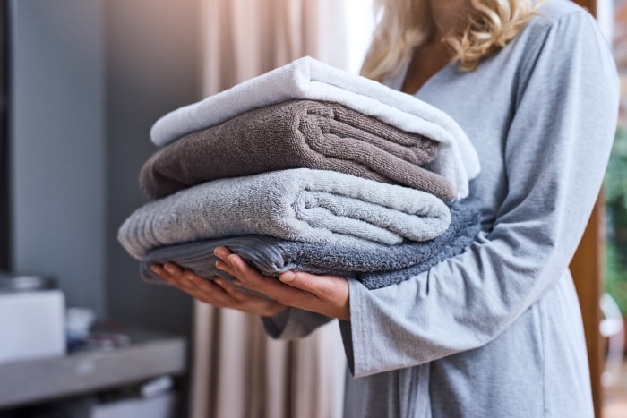 femme tenant une pile de serviettes de bain pliées