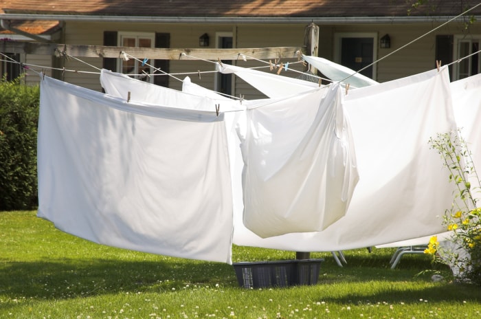 grands draps blancs ensoleillés suspendus à des cordes à linge dans l'arrière-cour d'une maison de banlieue