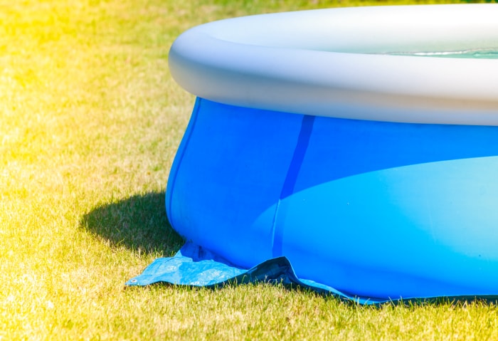 Piscine gonflable ronde bleue et blanche sur une pelouse jaune.