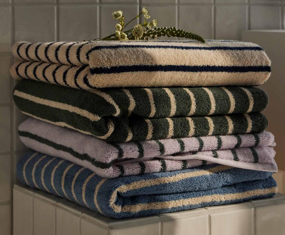 Stack of 4 Brooklinen Super Plush Turkish Cotton Bath Towels in different colors.