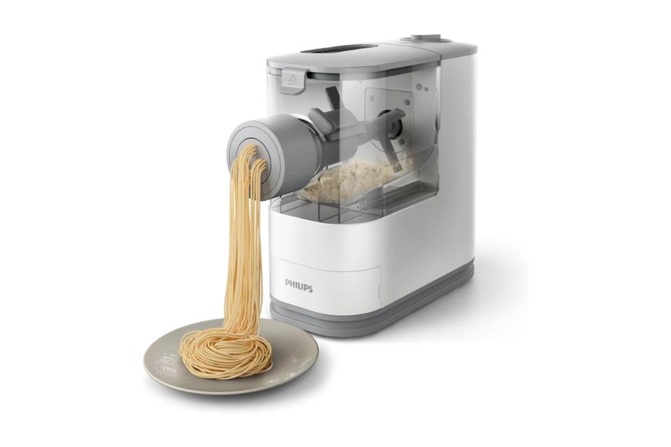 image of white Philips pasta machine with spaghetti noodles churning out onto a gray plate against white background 