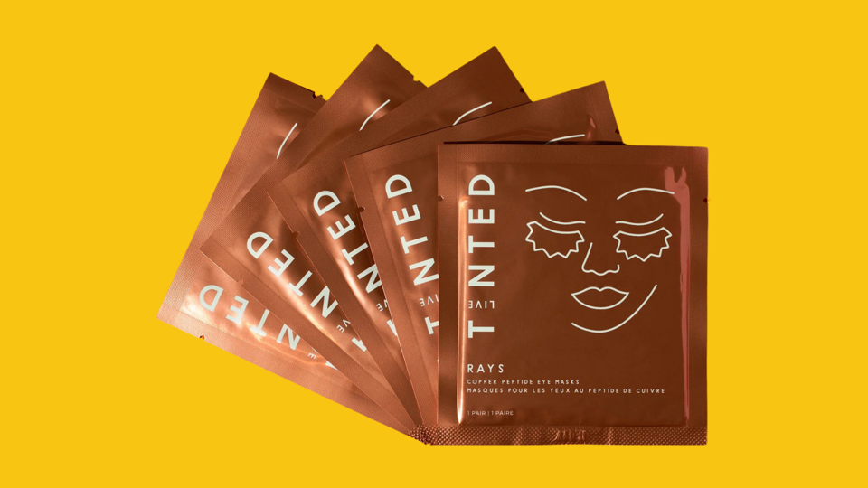 Live Tinted Rays Copper Peptide Eye Mask packages against yellow background