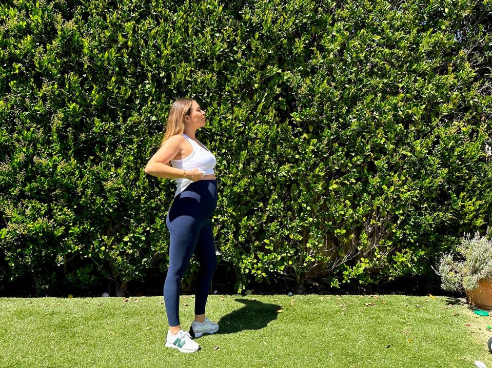 Author wearing the Beyond Yoga’s Spacedye Love the Bump Midi Maternity leggings on a lawn.