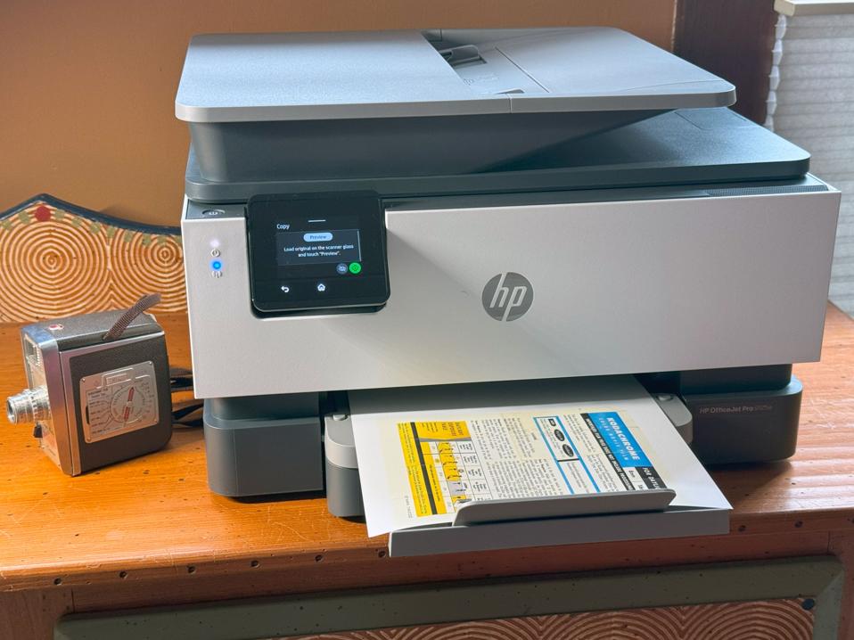 HP Officejet Pro 9125e on a desktop next to a vintage camera