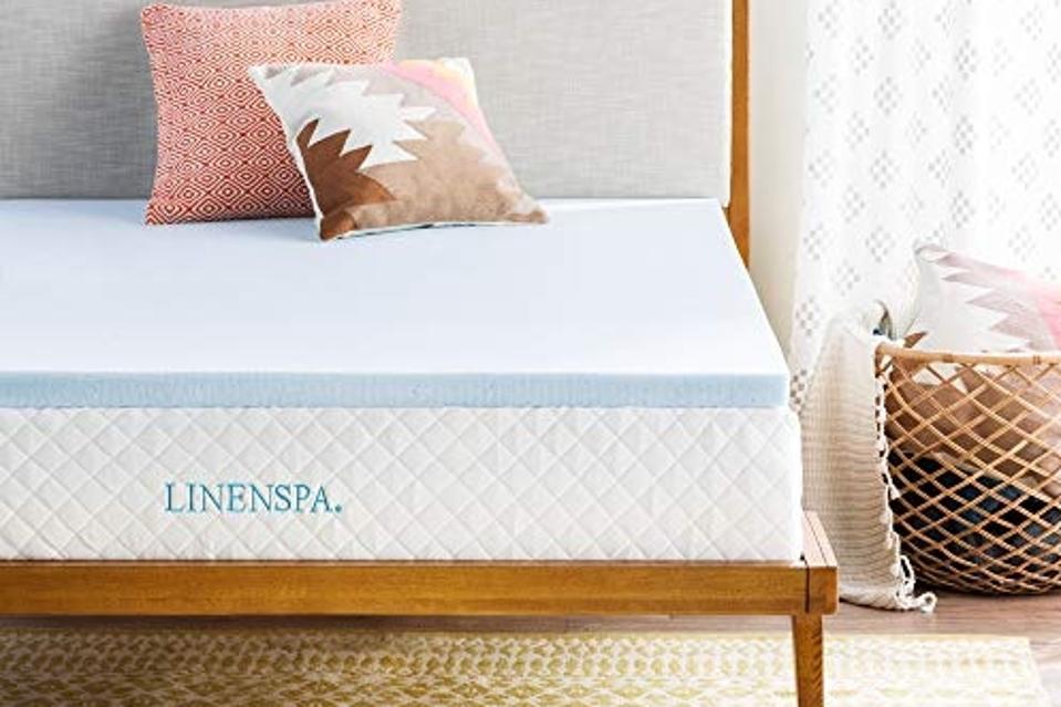 The Linenspa 2-inch Memory Foam Mattress Topper  on a mattress with pillows on it