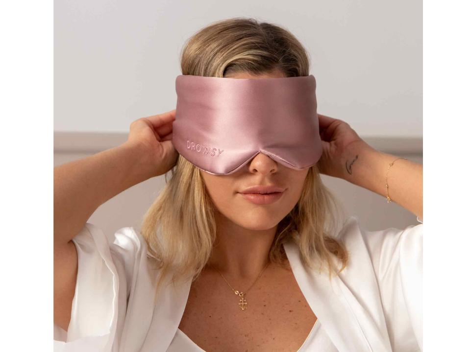 blond woman with damask rose drowsy sleep mask on against beige bg last-minute mothers day